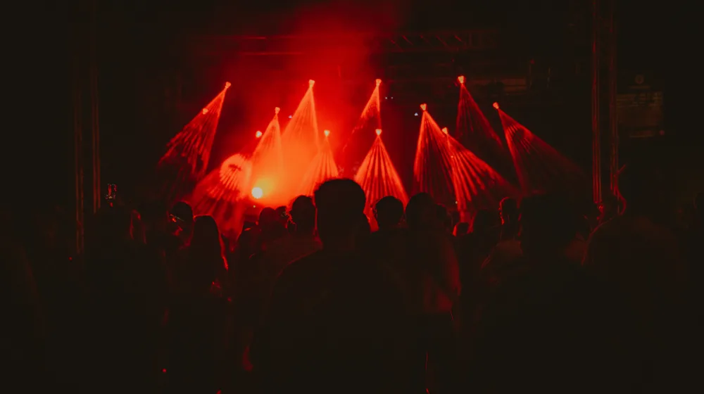 Crowd bathed in red light in front of the festival stage